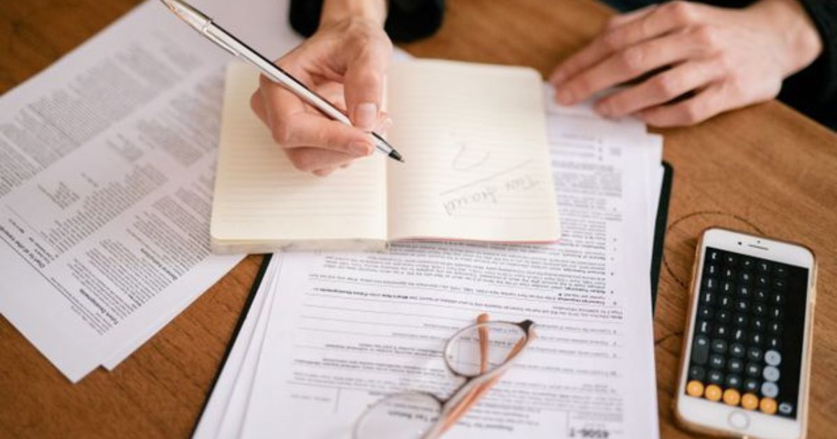Person writing notes near tax documents related to Rachel Reeves property tax policy