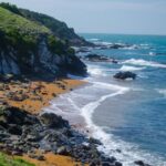 Kynance Cove beach in Cornwall featuring turquoise water, dramatic rock formations, golden sand, and stunning coastal scenery.