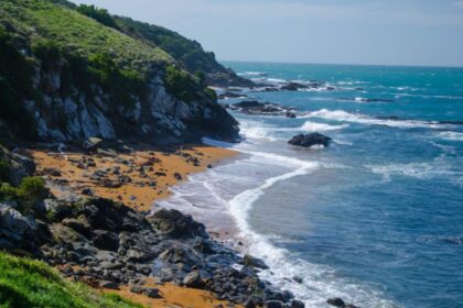 Kynance Cove beach in Cornwall featuring turquoise water, dramatic rock formations, golden sand, and stunning coastal scenery.