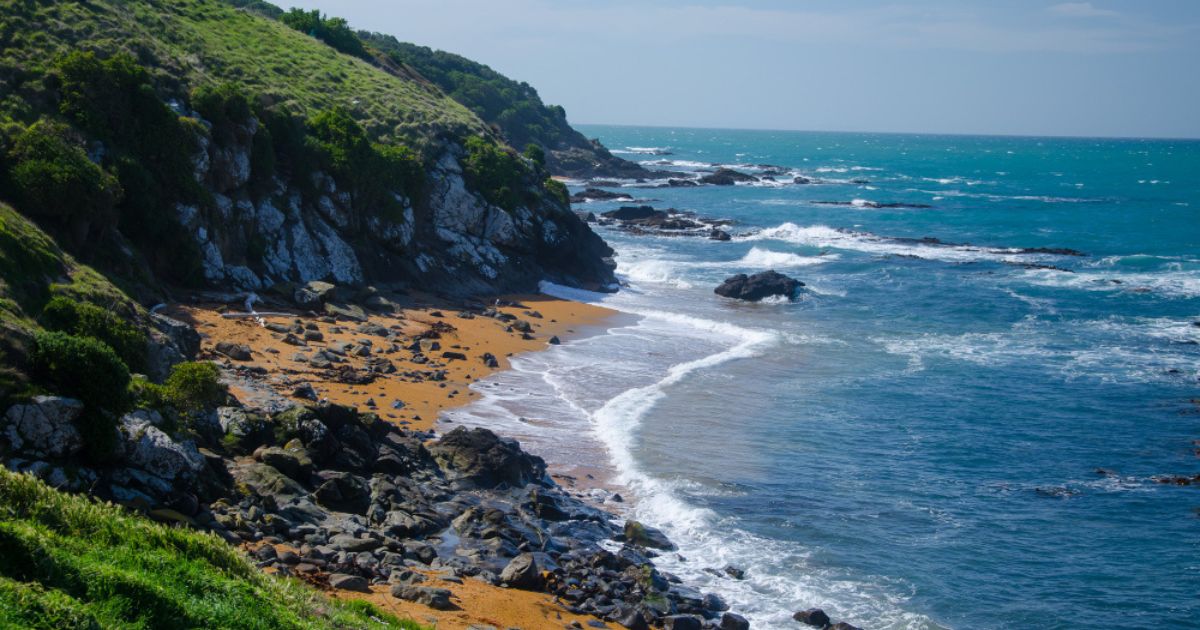 Kynance Cove beach in Cornwall featuring turquoise water, dramatic rock formations, golden sand, and stunning coastal scenery.