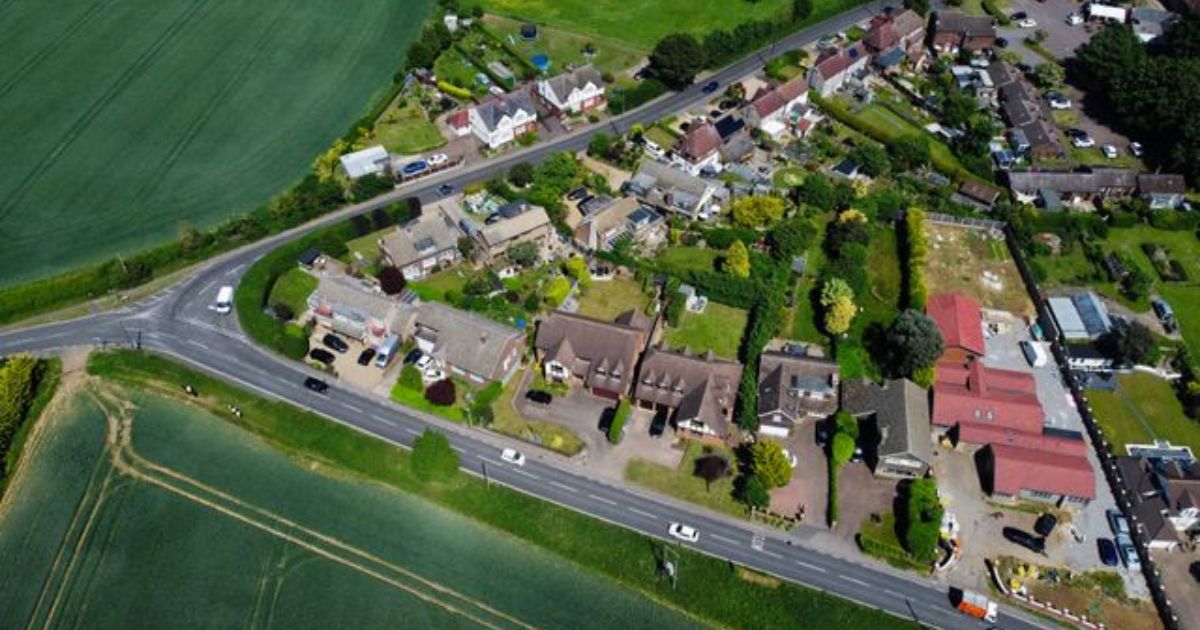 Aerial drone shot of a rural UK village with residential properties and surrounding land for property development advice UK