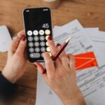 Person calculating tax figures on smartphone for Rachel Reeves property tax updates