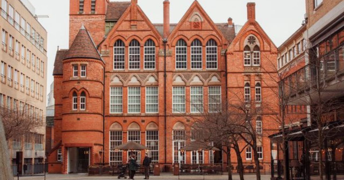 Birmingham Magistrates Court ki laal eint wali purani imaarat ki tasveer, jis ke saamne ek café patio aur kuch log dikhai de rahe hain.