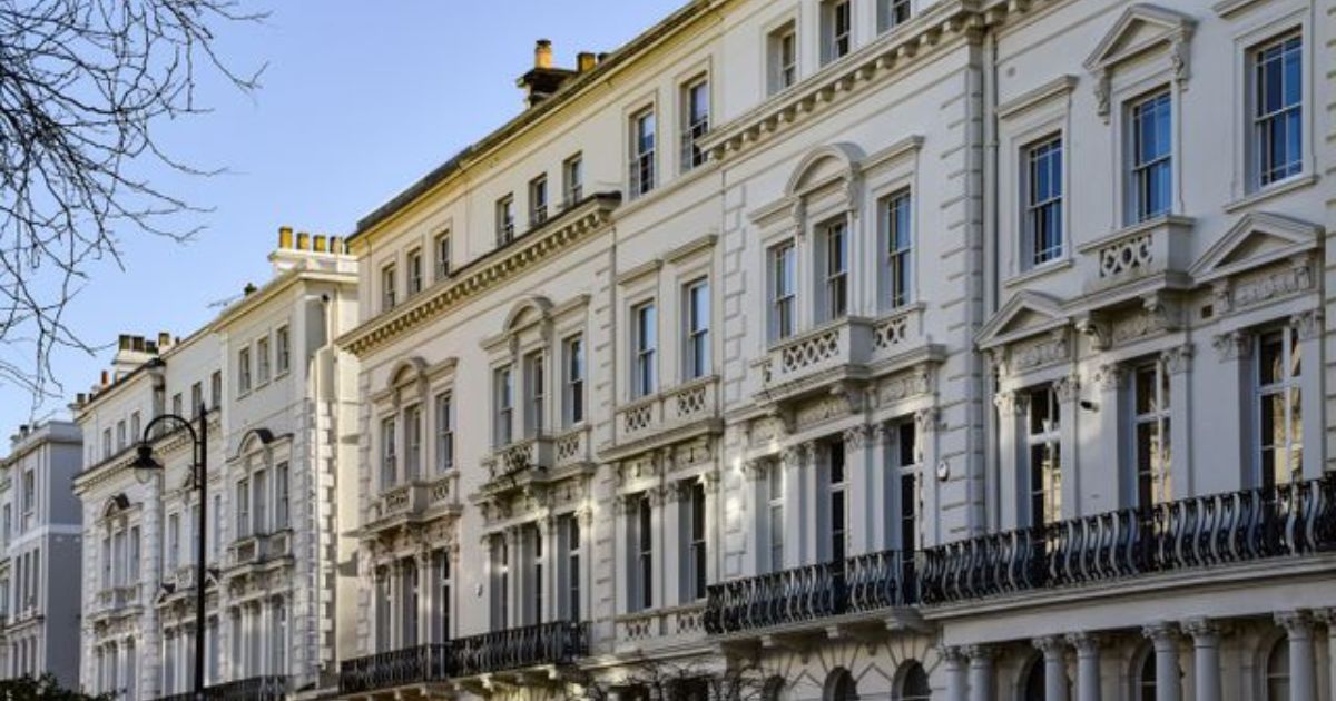 London mein purani Georgian tarze-tameer ki safaid imarat ki qatar, jis mein iron railings aur baramday nazar aa rahay hain.
