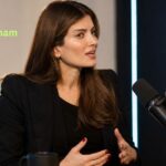 Laila Cunningham speaking during a studio podcast interview in a dark blazer