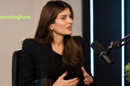 Laila Cunningham speaking during a studio podcast interview in a dark blazer
