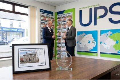 A framed Ulster Property Sales (UPS) listing document and award on a wooden desk in a professional Northern Ireland office.
