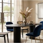 Black BD Studio Belle oval dining table styled with a ceramic vase and candles surrounded by blue velvet and cane chairs.